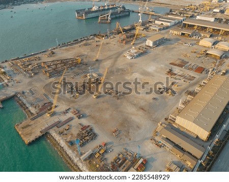 Aerial view of busy industrial under construction site workers working with cranes and excavators. Top view of precast concrete slap floor full of steel. Container port.