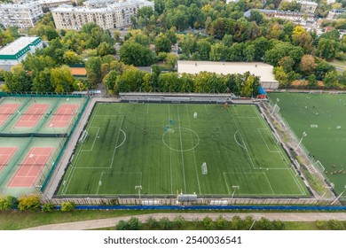 Aerial view of a busy sports complex featuring multiple soccer and tennis courts in a vibrant urban setting - Powered by Shutterstock