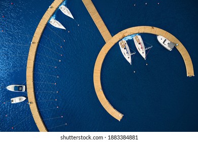 Aerial View by Drone of Yacht Club and Marina. Top view of yacht club. White boats in sea water. Marina dock yachts and small motor boats. Yacht and sailboat is moored at the quay. Parking