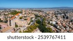 Aerial view of Cagliari, Sardinia, highlighting the Castello district with medieval architecture. Colorful buildings and greenery contrast with distant mountains.