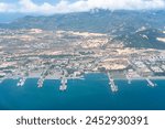 Aerial view of Cam Ranh, coastal landscape Vietnam. Container ships at industrial port in business logistic export import. Containers and wind turbine parts in cargo freight ships. Travel photo