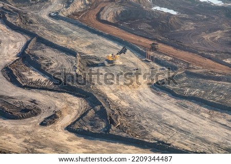 Aerial view of Canadian commercial excavator surface mining on site for Oilsands a giant dump truck loaded and heading to nearby refineries travel 