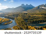 Aerial view of Canadian Rockies mountain range and Bow river forest in autumn morning. Canmore, Alberta, Canada. The Three Sisters trio of peaks.