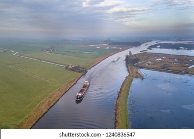 Aerial view of canal in Friesland with inland freight ships passing by. The Netherlands