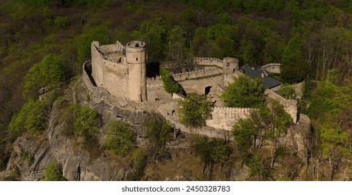 An aerial view captures the medieval Chojnik Castle atop a mountain in the Karkonosze range. The ancient fortress stands proudly amidst the scenic landscape, blending history with nature. - Powered by Shutterstock