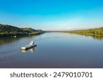 An aerial view captures a tugboat navigating the Ohio River between Indiana and Kentucky, gracefully sailing on a river amidst mountainous terrain.