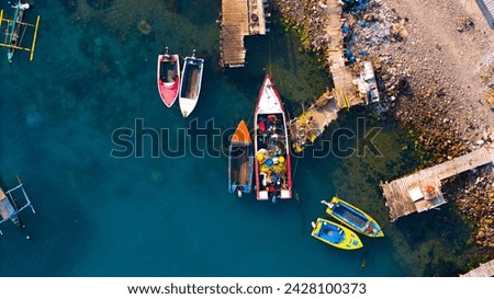 Aerial view captures vibrant boats moored by the rustic pier, showcasing a harmony of human activity and serene water