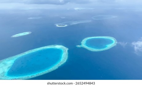 An aerial view capturing multiple round atolls surrounded by deep blue ocean