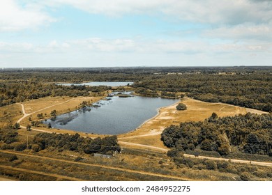 Aerial view capturing the tranquil Derryounce Lakes and surrounding walkways in Portarlington, County Laois. The landscape features a serene lake, lush greenery, and distant wind turbines under a part - Powered by Shutterstock