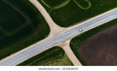 Aerial view of car driving on rural road intersection. Aerial shot of a car driving through a rural road intersection surrounded by green fields and farmland.
Latvia, spring - Powered by Shutterstock