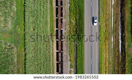 Aerial view of car driving, shot from drone directly above. The ute drives through the highway surrounded by lush green fields, old railway tracks and abandoned train carriages