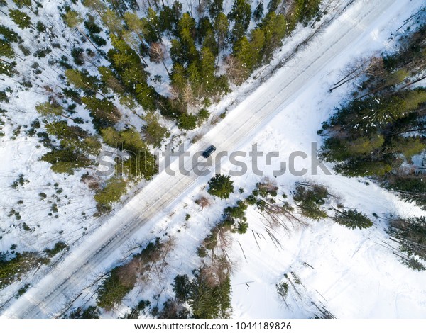 Aerial view of a car\
on winter road. Winter landscape countryside. Aerial photography of\
snow forest with a car on the road. Captured from above with a\
drone. Aerial photo. 