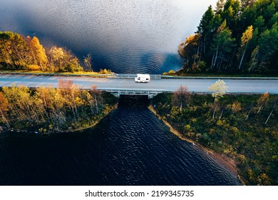 Aerial view Caravan trailer or Camper rv on the bridge over the lake in Finland. Autumn holiday trip.