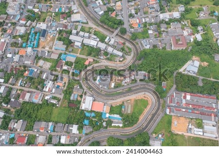 Aerial view of cars driving on curved, zigzag curve road or street on mountain hill with green natural forest trees in rural city town of Songkhla, Thailand. Transportation.