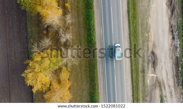 Aerial view of cars driving on country autumn\
road. Drone shot flying over rural\
road