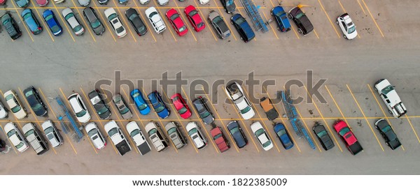 Aerial view\
of cars at large outdoor parking lots; USA. Outlet mall parking\
congestion and crowded parking lot; other cars try getting in and\
out; finding parking space.\
Panorama