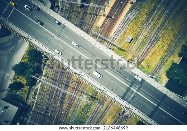 Aerial view of cars on an elevated expressway\
crossing railways. Cars overpassing railroad top down aerial view.\
Motorway flyover over\
railway