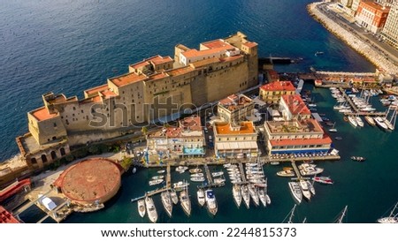 Aerial view of Castel dell'Ovo, a seafront castle located on a peninsula on the Gulf of Naples, Italy. There's a small fishing village called Borgo Marinaro, developed around the castle's eastern wall