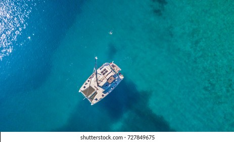 Aerial view of catamaran anchoring on coral reef. Bird eye view, water sport theme.