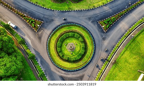 An aerial view of a circular intersection with multiple roads leading in and out, surrounded by lush greenery and decorative landscaping - Powered by Shutterstock