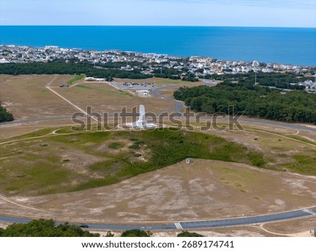 Aerial View Of Circular Road Loop Surrounding Hilltop Wright Brothers Monument With Outer Banks Coastline In Distance