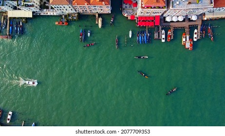 Aerial View Of The City On The Water And Rooftops, The Bell Tower Of The Basilica And The Unique Canals With Boats, Crossing Venice And Italy. Gondolas With Tourists. Carnival And Film Festival. Masks