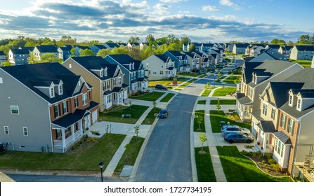 Aerial view of classic upper middle class neighborhood street with luxury single family homes with colorful siding for the up and coming with trees planted at equal distance in Maryland USA