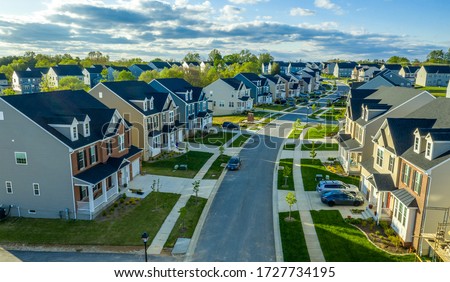 Aerial view of classic upper middle class neighborhood street with luxury single family homes with colorful siding for the up and coming with trees planted at equal distance in Maryland USA