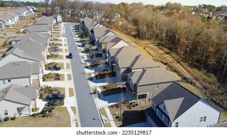 Aerial view clean HOA neighborhood residential streets parked car and front garage homes in new development subdivision outside Atlanta, Georgia, US. Two story houses well trimmed lawn large backyard