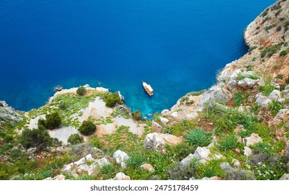 Aerial view of clear blue waters of Mediterranean sea and rugged coastline of Alanya, Turkey. Solitary boat floats serenely near rocky shore. Alanya is popular travel and holiday destination in Europe - Powered by Shutterstock