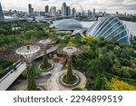 Aerial view to Cloud Forest and Flower Dome illuminated at the twilight. Famous hotel at the background. Gardens by the Bay, Singapore city.