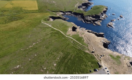 Aerial view of a coastal landscape with cliffs, green fields, and blue ocean water. - Powered by Shutterstock