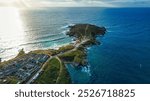 Aerial view of a coastal landscape featuring a peninsula extending into the ocean.  At Fistral Beach, Newquay, Cornwall, UK