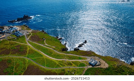 Aerial view of a coastal landscape featuring green hills, winding paths, and a sparkling blue ocean. At Land's End, Cornwall, UK. - Powered by Shutterstock