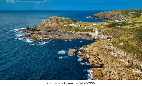 Aerial view of a coastal landscape featuring rocky shores, clear blue waters, and a green hillside. At Cape Cornwall, UK. - Powered by Shutterstock