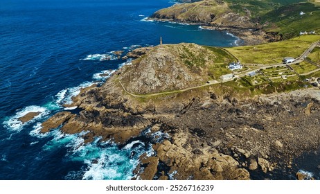 Aerial view of a coastal landscape featuring rocky shores, a lighthouse on a hill, and lush green hills in the background. At Cape Cornwall, UK. - Powered by Shutterstock