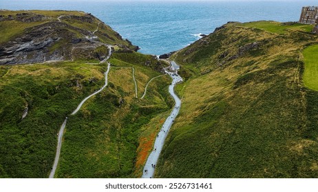 Aerial view of a coastal landscape featuring winding paths leading down to the sea. In Tintagel, Cornwall, UK. - Powered by Shutterstock