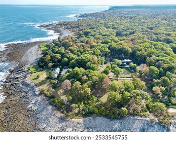 Aerial view of a coastal landscape with lush green trees, rocky shoreline, and ocean waves, showcasing a serene natural environment. - Powered by Shutterstock