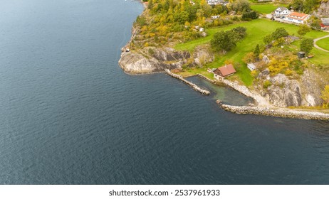 Aerial view of a coastal landscape with rocky shoreline, green vegetation, and a small dock extending into the water. - Powered by Shutterstock