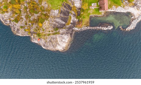 Aerial view of a coastal landscape with rocky shoreline, green vegetation, and a small dock extending into the water. - Powered by Shutterstock