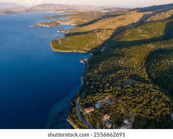 Aerial view of a coastal road winding through lush green hills, meeting the deep blue sea. - Powered by Shutterstock