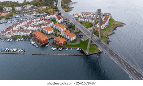 Aerial view of a coastal town with a bridge, red-roofed houses, and a marina. - Powered by Shutterstock