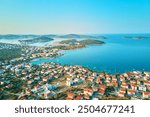 Aerial view of coastal town with colorful buildings near sea coastline. Touristic city for summer vacation with red roof houses and Islands in Adriatic sea. Panoramic view of Rogoznica town in Croatia