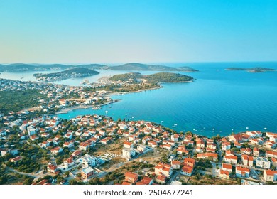 Aerial view of coastal town with colorful buildings near sea coastline. Touristic city for summer vacation with red roof houses and Islands in Adriatic sea. Panoramic view of Rogoznica town in Croatia - Powered by Shutterstock