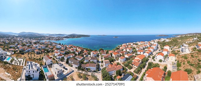 Aerial view of coastal town with colorful buildings near sea coastline. Touristic city for summer vacation with red roof houses and Islands in Adriatic sea. Panoramic view of Rogoznica town in Croatia - Powered by Shutterstock