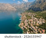 Aerial view of a coastal town nestled between mountains and sea in Montenegro during a sunny day