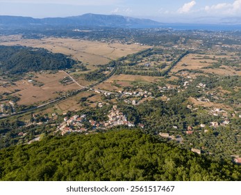 Aerial view of a coastal town nestled amidst lush greenery and farmland, overlooking a serene sea. - Powered by Shutterstock