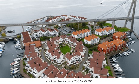 Aerial view of a coastal town with red-roofed houses, a marina, and a bridge. - Powered by Shutterstock