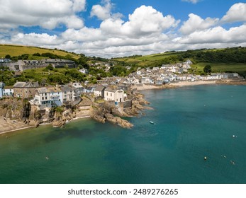 Aerial view of a coastal village with houses on cliffs and a clear blue sea in Cornwall, England - Powered by Shutterstock