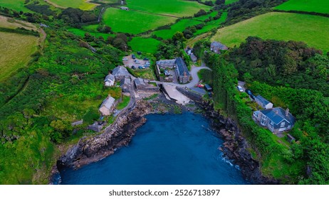 Aerial view of a coastal village surrounded by lush green fields and rocky shores. In Cornwall, UK. - Powered by Shutterstock